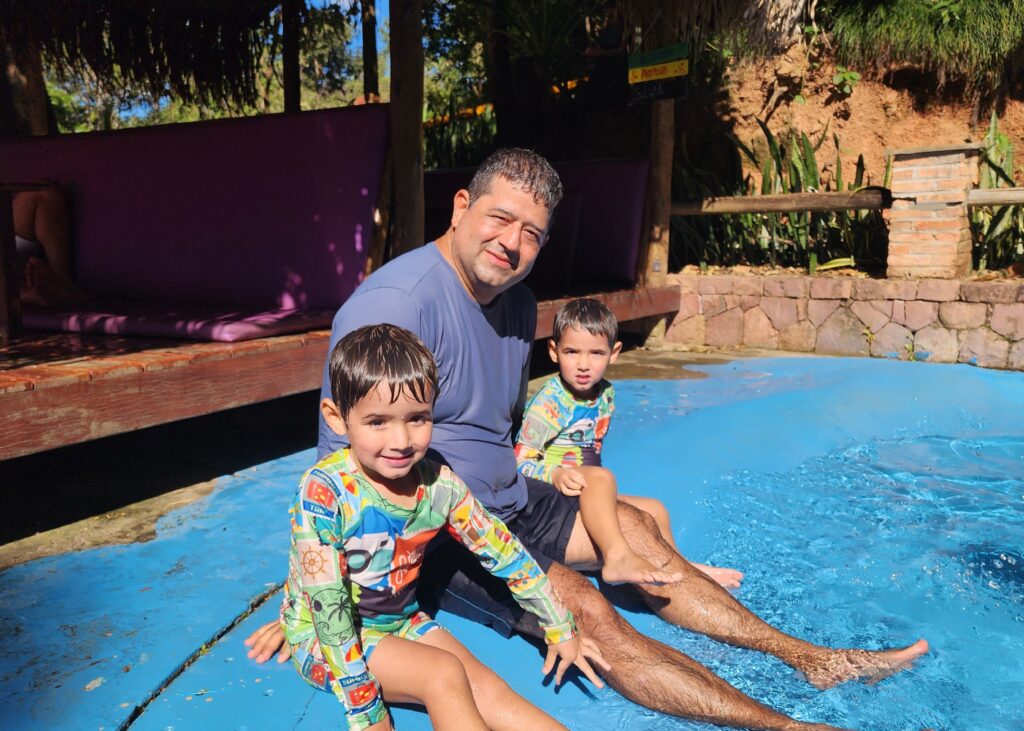 Pai e filhos gêmeos curtindo a piscina.