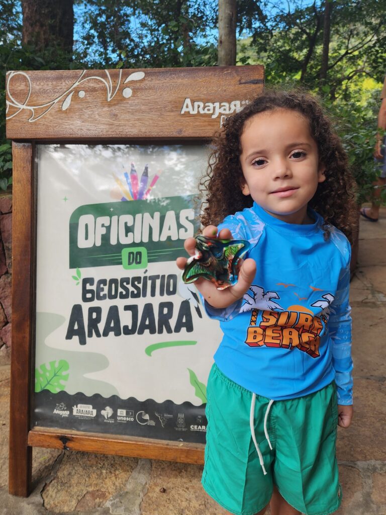 Criança em frente á placa de identificação das Oficinas do Geossítio Arajara. Uma das atraçõesde outubro do Arajara Park.